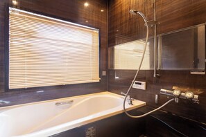 Un baño moderno con bañera, ducha y un espejo grande.