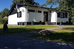 Ein zweistöckiges Haus mit weißer Fassade, schwarzer Verzierung und einem Eingang mit Treppe.