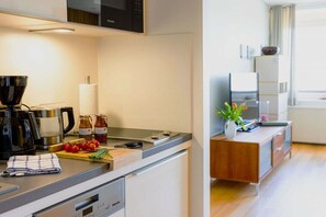 Eine moderne Küche mit Kaffeemaschine, Toaster und Schneidebrett mit Tomaten.