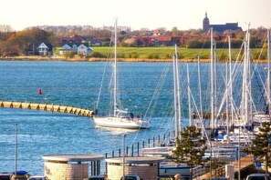 Ein Yachthafen mit Booten, einem Leuchtturm und Häusern im Hintergrund.