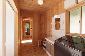 Interior de una cabaña de madera con kitchenette, un lavabo y un ventanal.