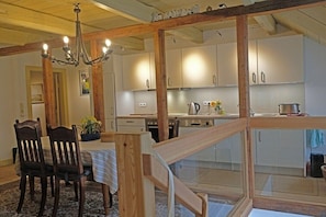 Eine Küche mit Holzbalken, weißen Schränken, einer Chandelier und einem Essbereich mit Stühlen und Tisch.