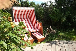 A wooden deck with a striped beach chair and a plant with yellow fruits. - Holiday apartment with 1 bedroom (Stoltenberg)