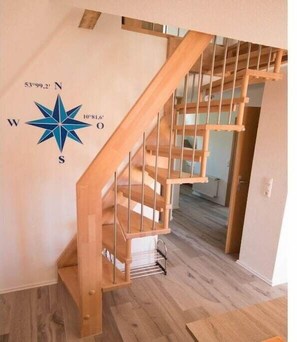 Eine Holztreppe mit Metallgeländer, einer Kompass-Wanddekoration und einem Holzboden.