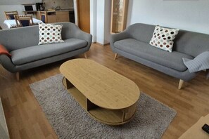 Ein Wohnzimmer mit zwei grauen Sofas, einem Holztisch und einem grauen Teppich.