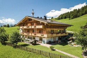 Eine zweistöckige Holzhütte mit Balkonen, einem Steinfundament und einem umlaufenden Holzzaun.