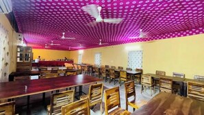 Une salle de conférence dotée de plusieurs tables et chaises, de ventilateurs de plafond et d’un plafond orné de motifs.