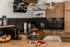 Eine moderne Küche mit Holzausstattung, einer Kaffeemaschine, einer Obstschale und einem Kreidetafel-Schild.