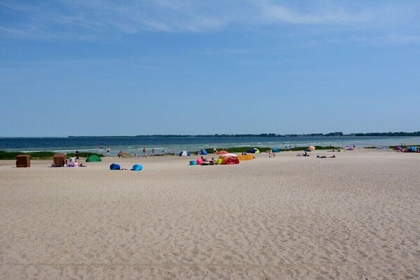 Ein Strand mit Zelten und badenden Gästen.