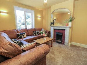 A living room with a brown leather sofa, a coffee table, a fireplace, and a large mirror. - 8 Manor Villas (Totland Bay)
