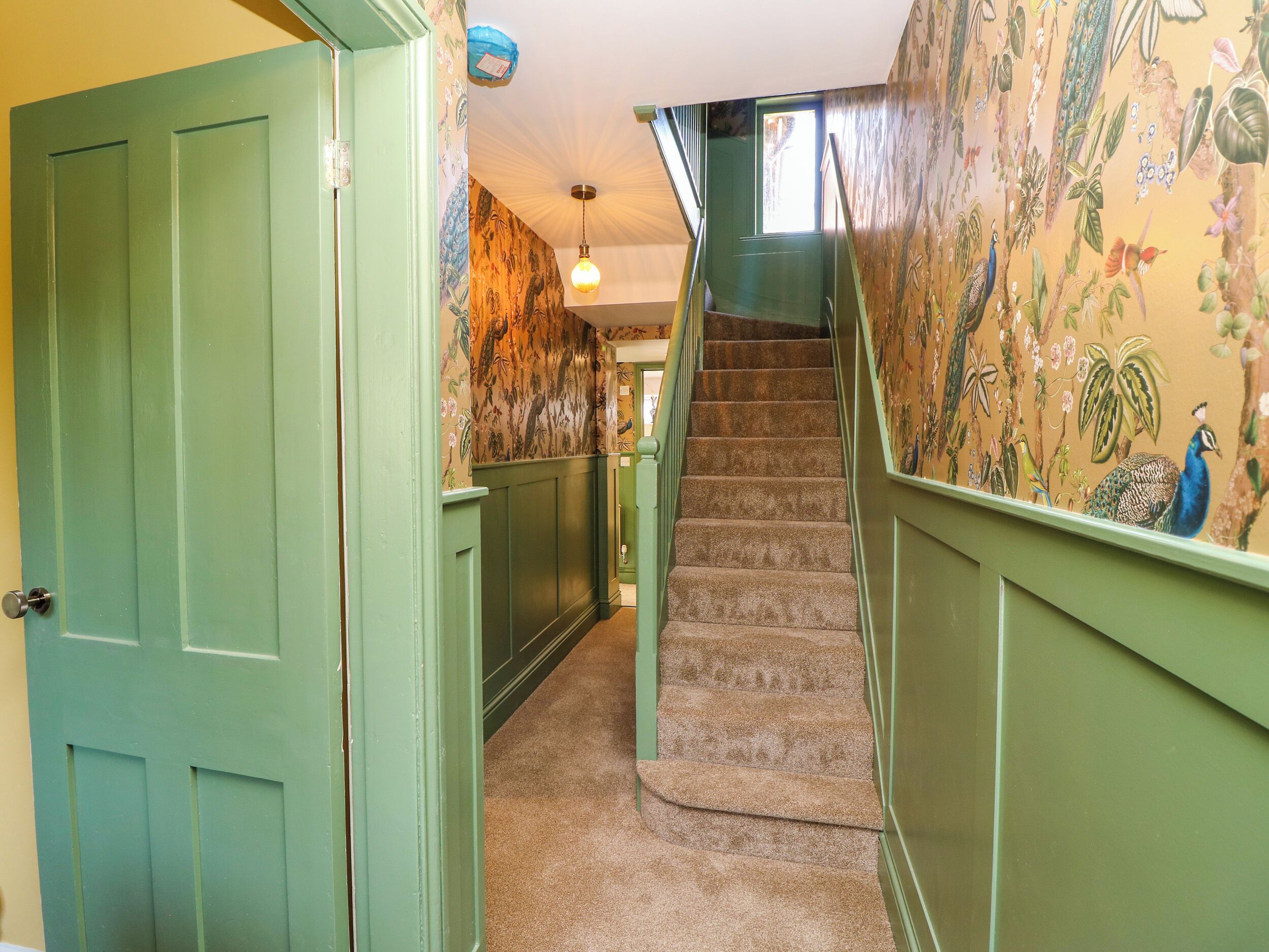 Un escalier dont les marches sont recouvertes de moquette et les murs peints en vert.