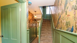 Un escalier dont les marches sont recouvertes de moquette et les murs peints en vert.