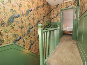 A hallway with floral wallpaper and green railings leading to a bedroom. - 8 Manor Villas (Totland Bay)