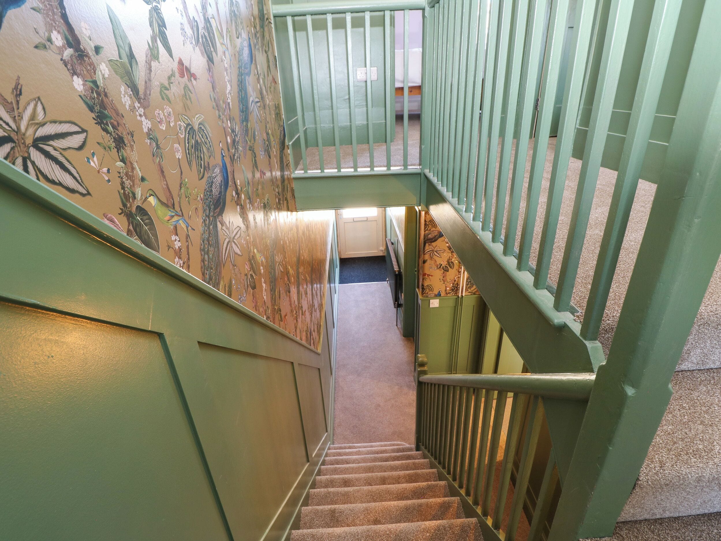 A staircase with green railings and a floral wall mural.
