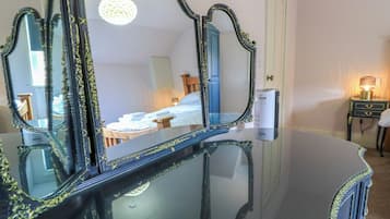 Quarto com um espelho grande, uma cama, uma mesinha de cabeceira com abajur e aquecedor fixado na parede.
