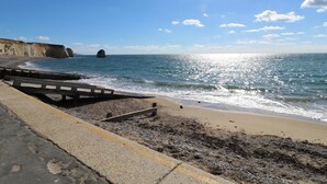 Une route côtière bordée d’une plage et de falaises.