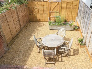 A wooden table and chairs in a garden area with a wooden fence and planters. - 8 Manor Villas (Totland Bay)