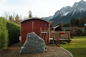 Ein rotes Holzgebäude mit einem Schild, einem großen Felsen davor und einem Berg im Hintergrund.