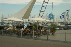 A marina with boats, outdoor seating, and a clear sky. - Villa by the sea 64-Seaside (Grömitz)