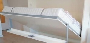A room with a bed, a bedside table, and a wall-mounted shelf. - Villa by the sea 64-Seaside (Grömitz)