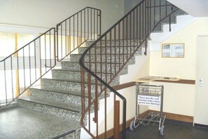 A staircase with a metal railing, a sign in German, and a cart with a sign. - Villa by the sea 64-Seaside (Grömitz)