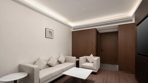 Una sala moderna con sofá, sillón, mesa de centro y una mesita auxiliar.