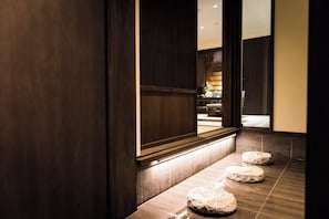Ein Korridor mit Holzwänden und Fliesenboden, der zu einem Raum mit einer sichtbaren Treppe führt.