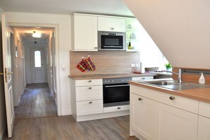 Eine Küche mit weißen Schränken, einer Mikrowelle, einem Backofen und einem Spülbecken.