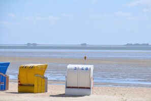 Strandliegen mit den Nummern 148 und 149 an einem sandigen Strand mit ruhiger See und weiter Küste.