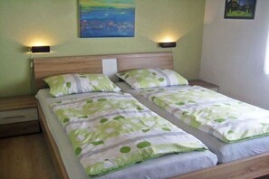 Ein Doppelbett mit grün-weißer Bettwäsche, zwei Nachttischlampen und ein Gemälde an der Wand.