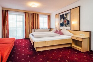 A hotel room with a bed, a nightstand, a red carpet, and a window with curtains. - Apartment with mountain view (Ladis)