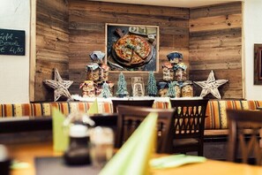 A restaurant interior with wooden walls, a pizza on display, and various food items on the counter. - Apartment with mountain view (Ladis)