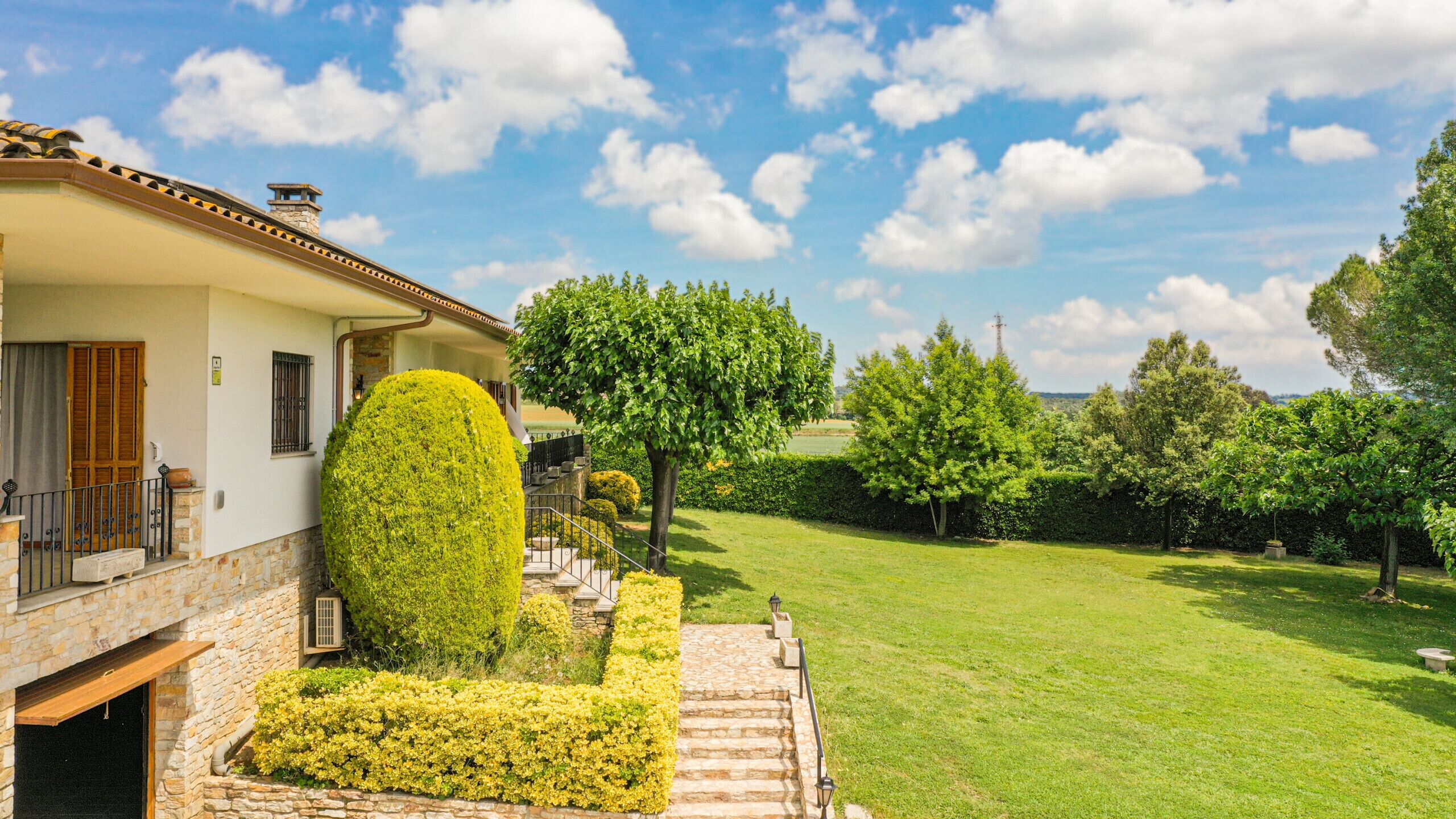A house with a stone facade, a well-maintained lawn, and a clear sky.