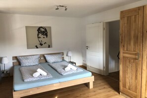 Ein Schlafzimmer mit einem Bett, zwei Nachttischlampen, einem Holzschrank und einer Tür.