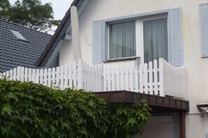 Ein Haus mit weißem Zaun, Fensterläden in Blau und ein graues Dach.