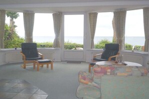 Ein Zimmer mit zwei schwarzen Stühlen, einem kleinen Tisch und einem farbenfrohen Sofa.
