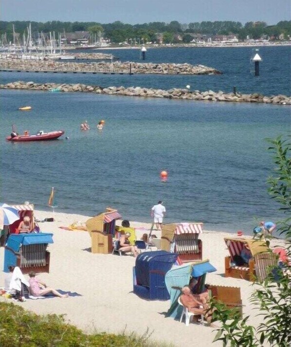 Ein Strand mit Menschen, Booten und einer felsigen Küste.