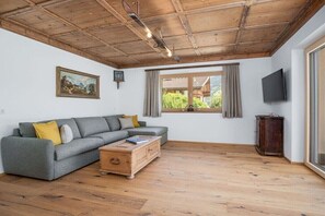Ein Wohnzimmer mit einer Couch, einem Holztisch und einem Fernseher.