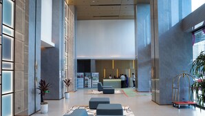 Een moderne lobby met een receptiebalie, een zithoek en potplanten.