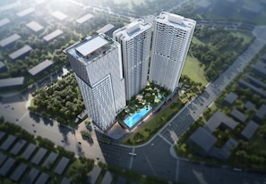 A high-rise building with multiple floors, surrounded by greenery and a swimming pool. - Itadaki Suite (Phnom Penh)