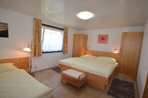 Ein Schlafzimmer mit einem hölzernen Bett, einem Fenster mit Vorhängen, einer Nachttischlampe und einer kleinen Holzbank.
