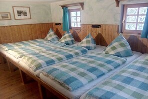 Ein Zimmer mit einem Holzbett, zwei Fenstern und Holzboden.