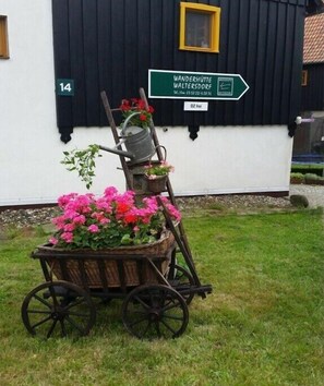 A cart with flowers in front of a building with a sign indicating 'Wanderhütte Waltersdorf.' - Waltersdorf hiking hut (Bad Schandau OT Waltersdorf)