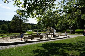 Ein Park mit Picknicktischen, einer Schaukel und einem kleinen Gebäude.