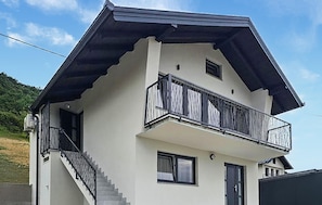 Ein zweistöckiges Gebäude mit Balkon, Treppe und einer Tür.