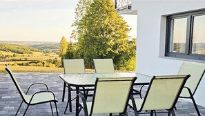 Un patio con tavolo e sedie, vista su un albero e un edificio sullo sfondo.