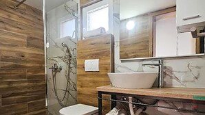 A bathroom with a wooden wall, a white sink, a mirror, and a shower. - 3 bedroom cozy home in Kalnik (Kalnik)