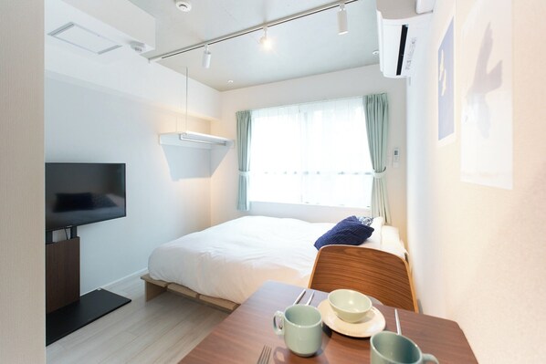 A hotel room with a bed, a TV, a table with a bowl and mug, and a window with curtains. - Monthly Rental A2 201  4minute walk from Sangenjaya Station  Maximum 2 people  WiFi / Setagaya Ward Tokyo (Setagaya Ward)