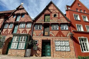 Um edifício tradicional de tijolos vermelhos com telhado íngreme, várias janelas e porta verde.