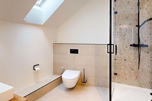Ein modernes Badezimmer mit Oberlicht, Toilette, Bidet und Duschbereich.